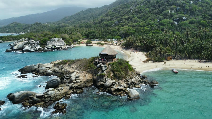 Vista aerea su una lingua di sabbia che ospita una casetta in mezzo al mare con dentro delle amache a cabo san juan nel Parco Tayrona in Colombia.