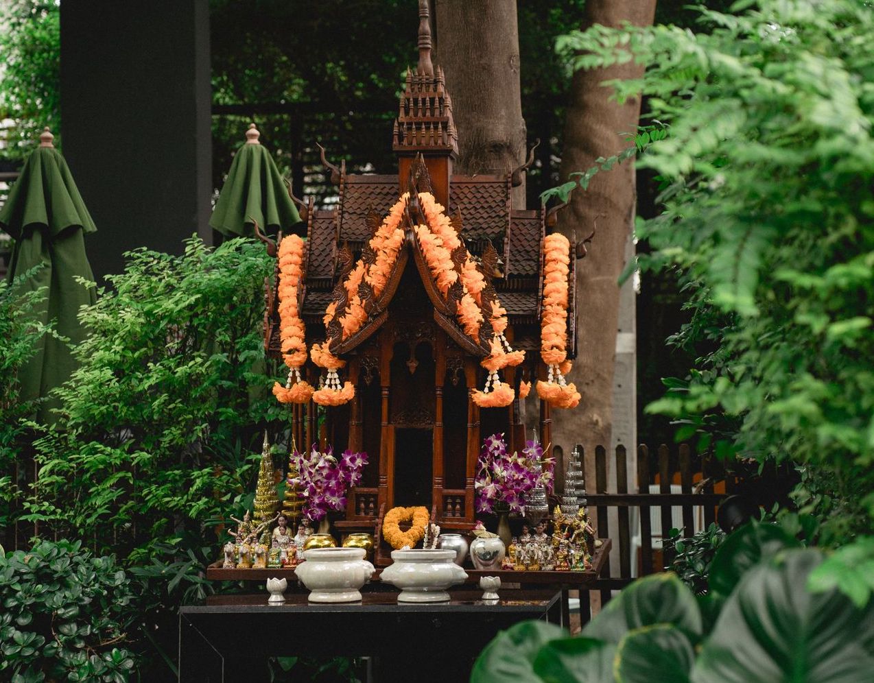 Una casetta di legno legno, adornata con fiori e offerte, in Thailandia