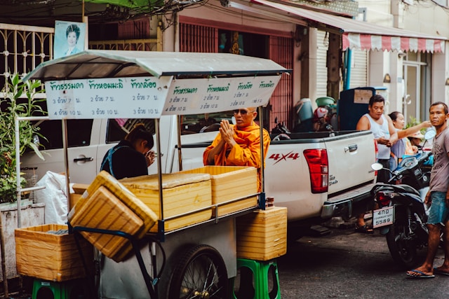 Due persone si salutano per strada con il tipico gesto del wai in Thailandia