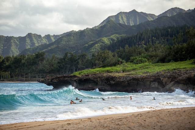 Persone cavalcano le onde in una spiaggia delle Hawaii