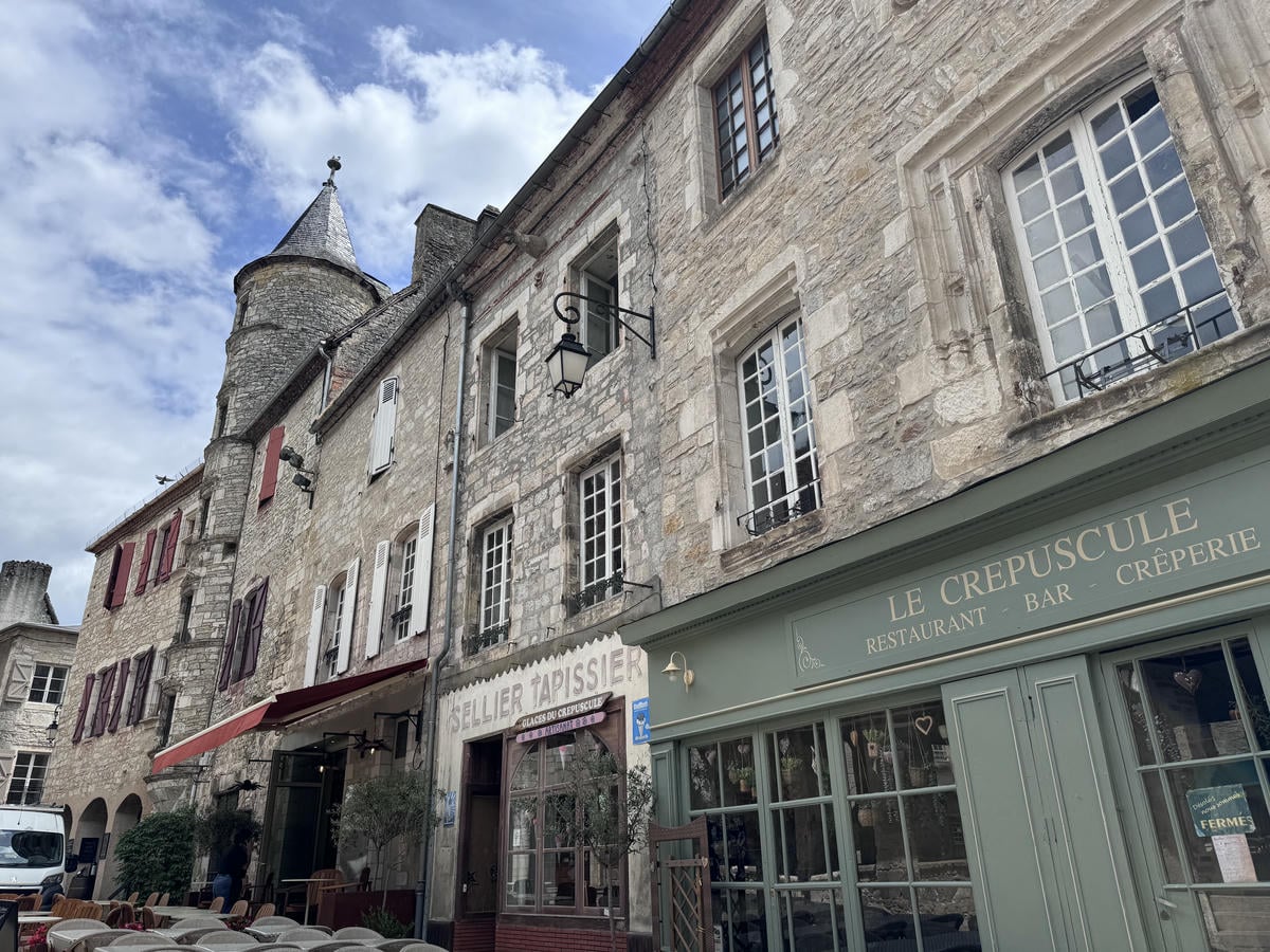 Edifici tipici francesi che circondano una piazza, in fondo svetta una torre, simbolo della città di Martel in Francia