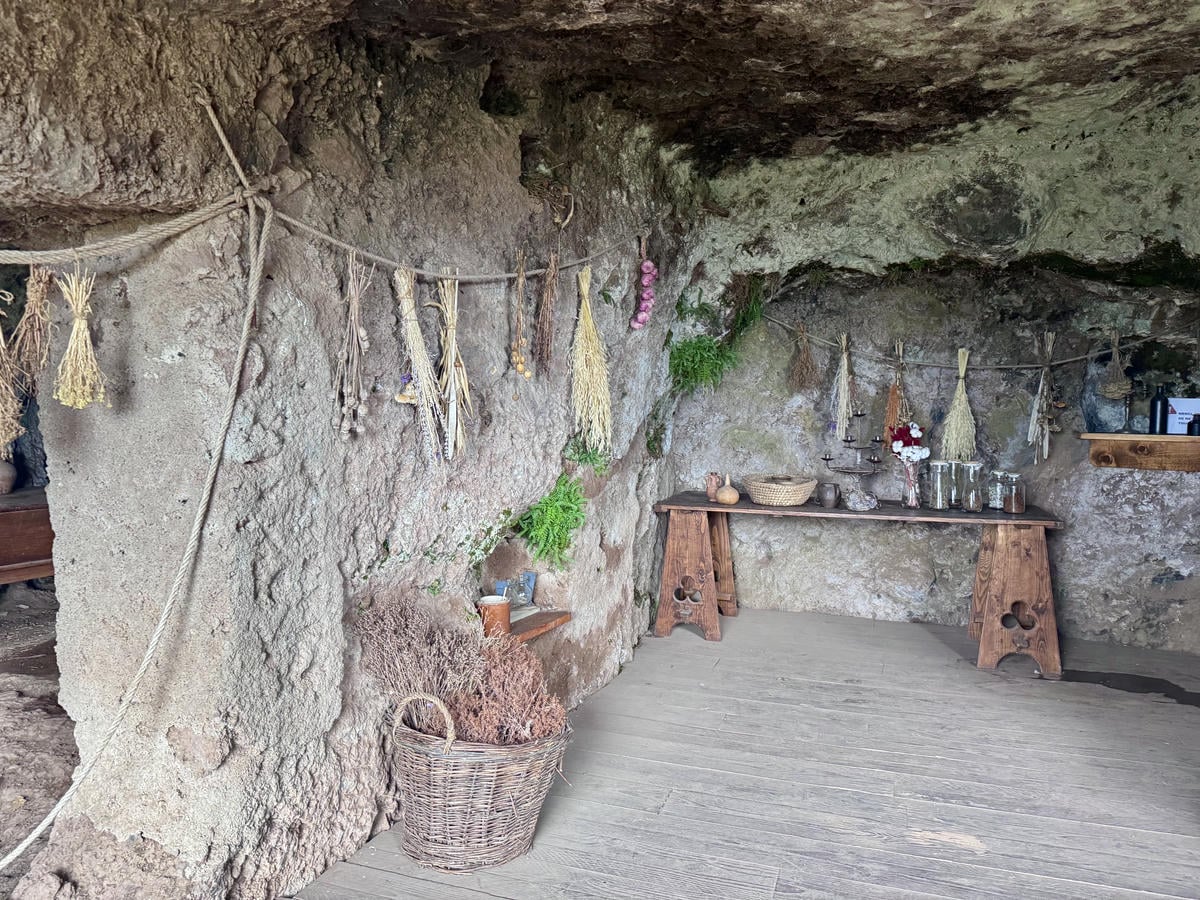 Stanza che ospitava la cucina e la dispensa. Sono appesi rametti di erbe essicate e disposti diversi contenitori.