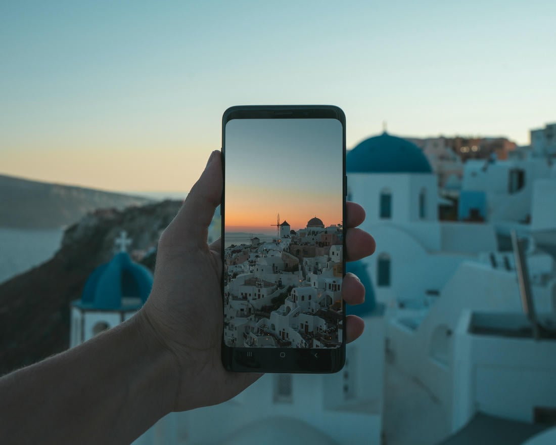 Uno smartphone mostra l'immagine del paesaggio si Santorini all'ora del tramonto