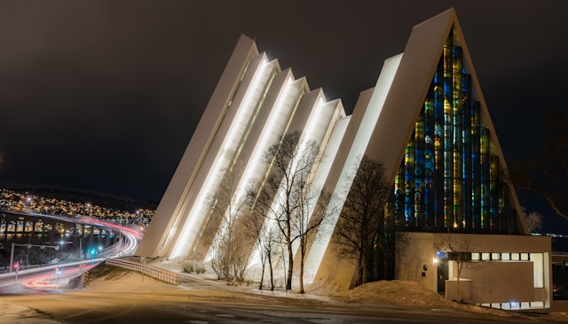 Cattedrale a forma piramidale illuminata di notte con la città di Tromso