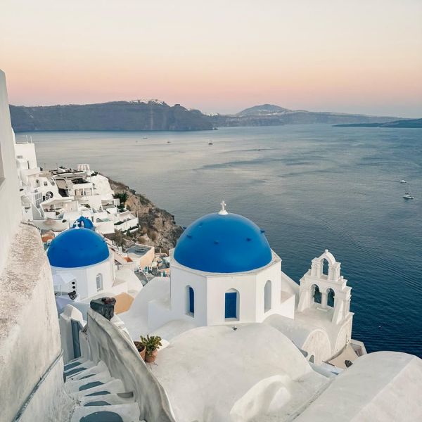 Vista splendida da una scalinata sulle casette bianche con cupole blu a Santorini all'ora del tramonto.